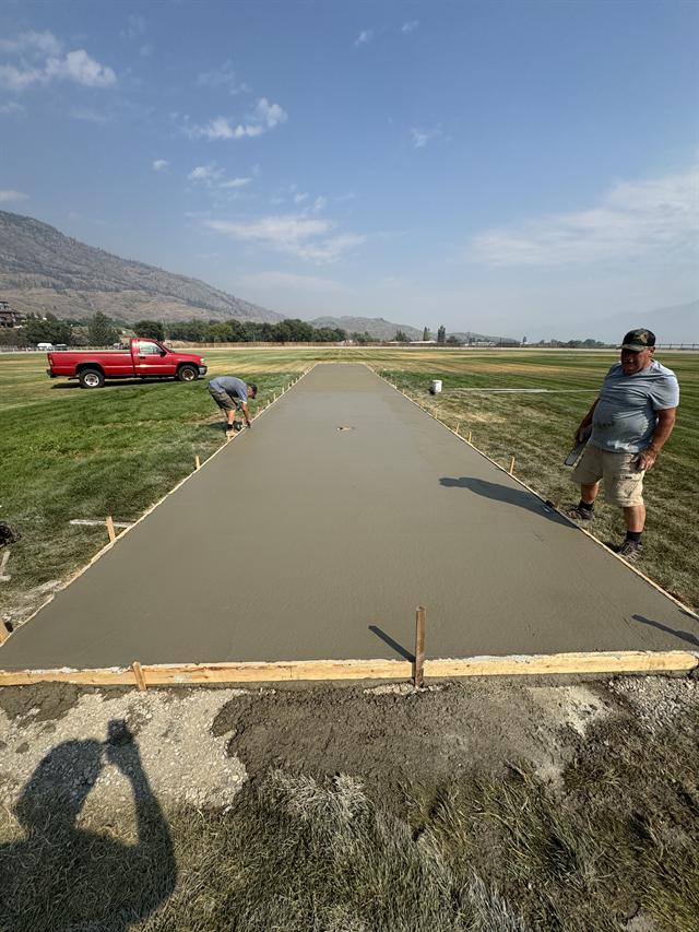 Crew member hand-finishing a fresh concrete pad above the Okanagan valley
