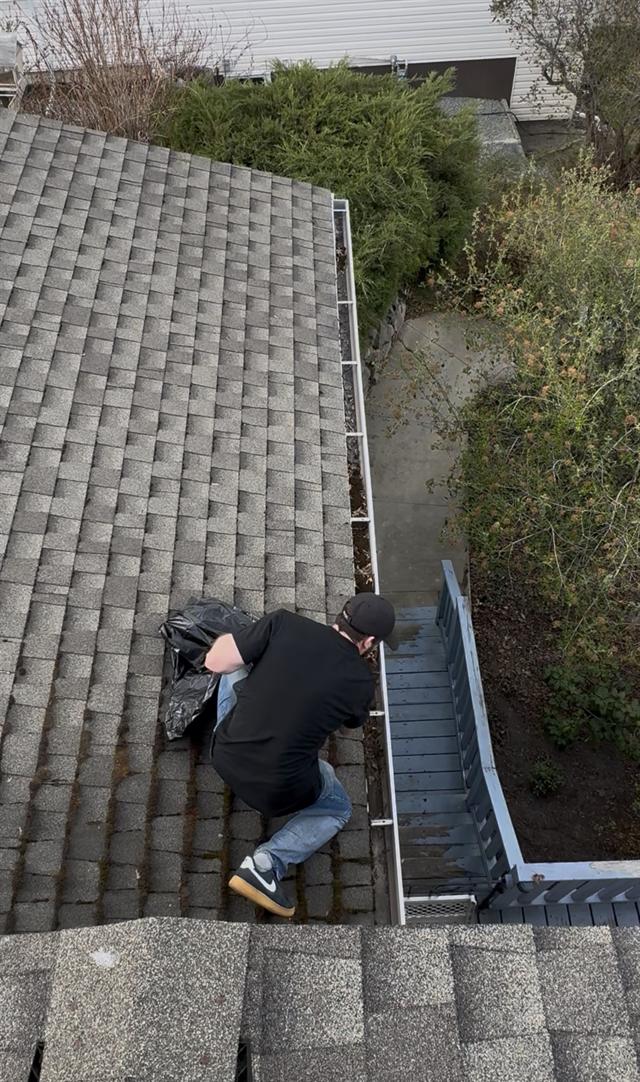 Worker clearing debris from a roof gutter