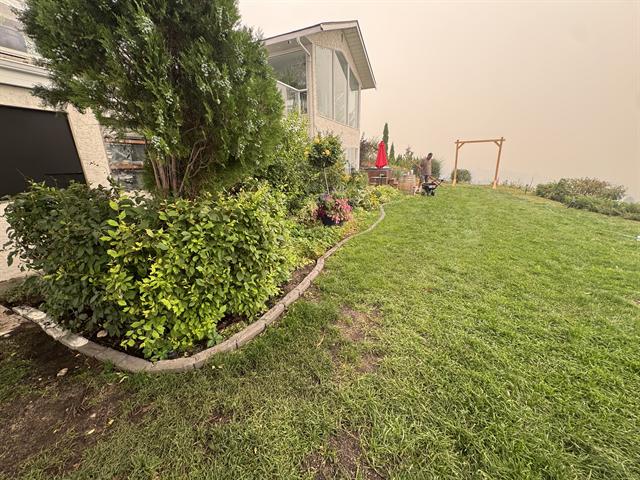 Manicured lawn with curbed garden beds and mature shrubs