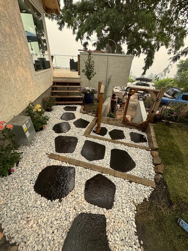 Charcoal stepping stones set into white decorative rock beside a patio
